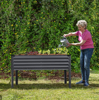 woman watering a raised garden bed with legs