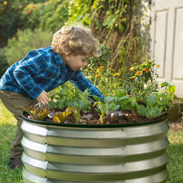 a round galvanized raised garden bed with a child planting