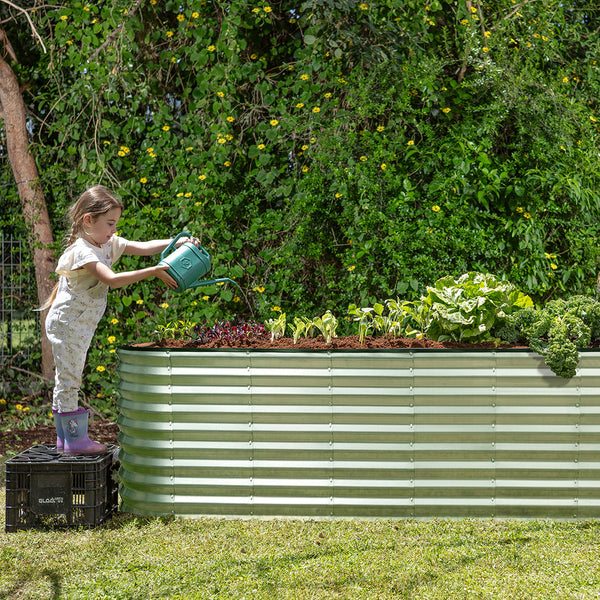 child watering a raised planter box